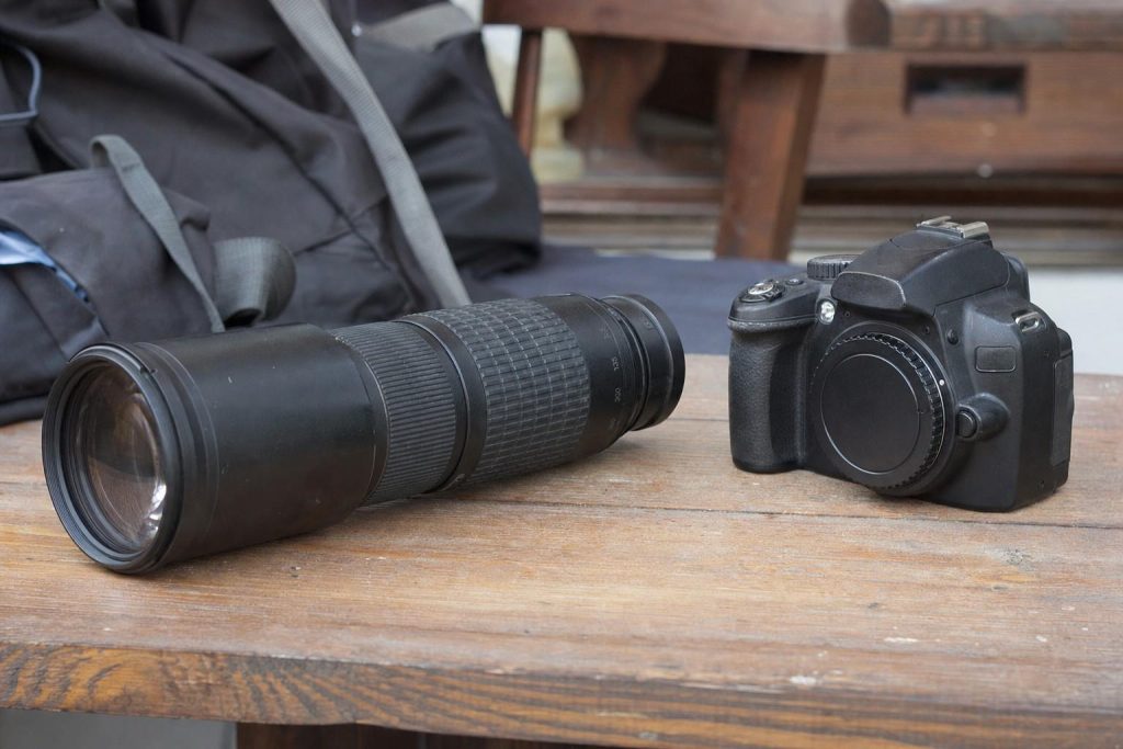 A telephoto zoom lens beside a camera body on a table