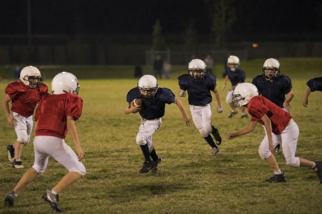 A youth football game under stadium lights at night
