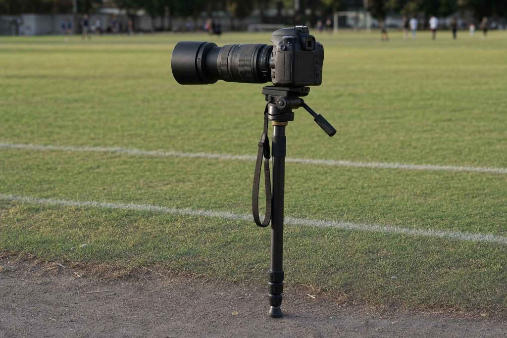 A camera on a monopod planted at the edge of a sports field