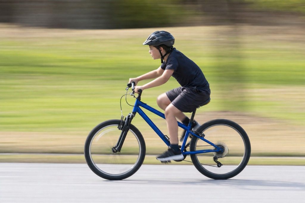 A panned photo of a young cyclist, sharp subject and streaked background