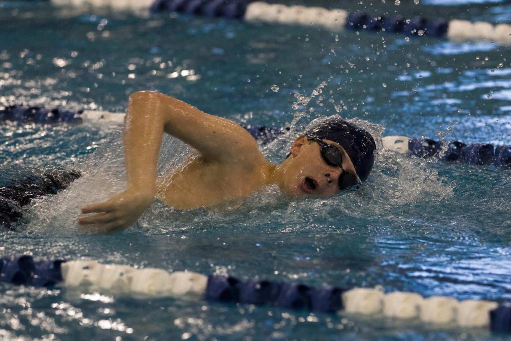 A youth swimmer mid-stroke in an indoor pool lane