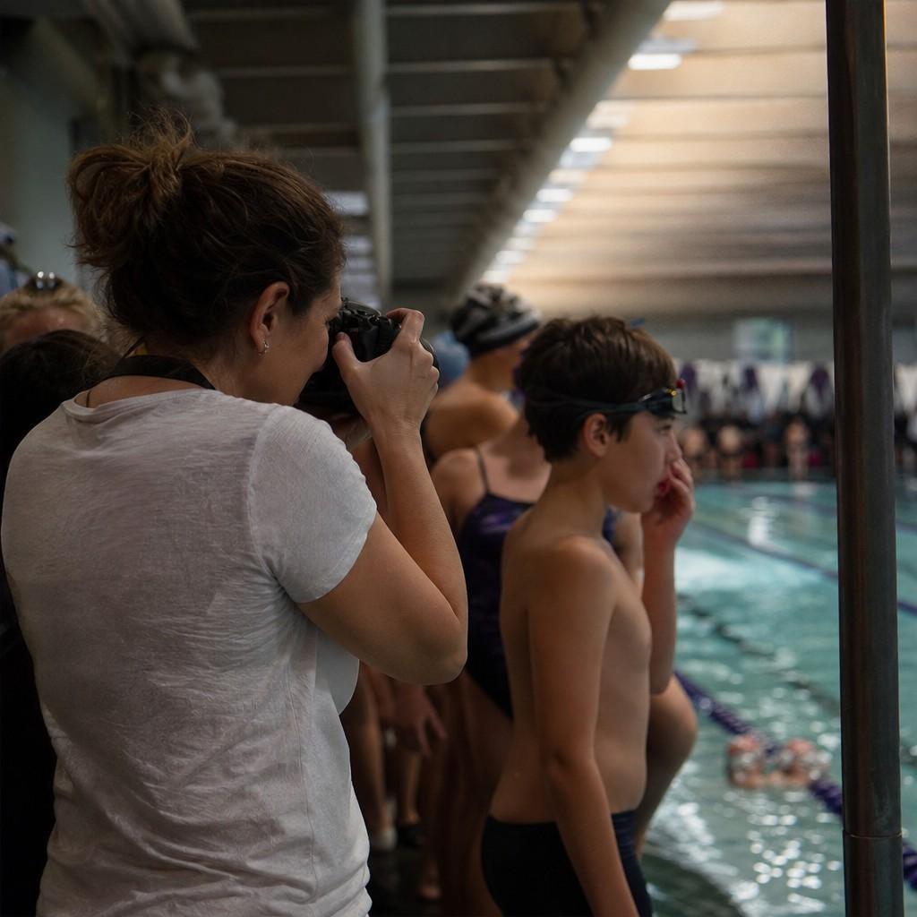 A parent photographing a swim meet from poolside